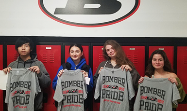  students hold up t-shirts after named students of the month